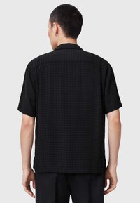 Schwarzes Kurzarmshirt aus strukturiertem Stoff, mit einem lässigen Schnitt und einem klaren Kragen-Design mit dezenten Gittermustern.