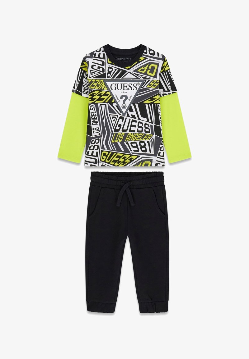 Zweiteiliges Outfit mit einem schwarzen, gemusterten Langarmshirt mit neongrünen Akzenten und schwarzen, zulaufenden Jogginghosen mit elastischem Bund.