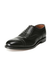 Chaussure habillée en cuir noir avec un bout rond, des détails type "wingtip" et des perforations. Elle présente un design à lacets et un talon robuste.
