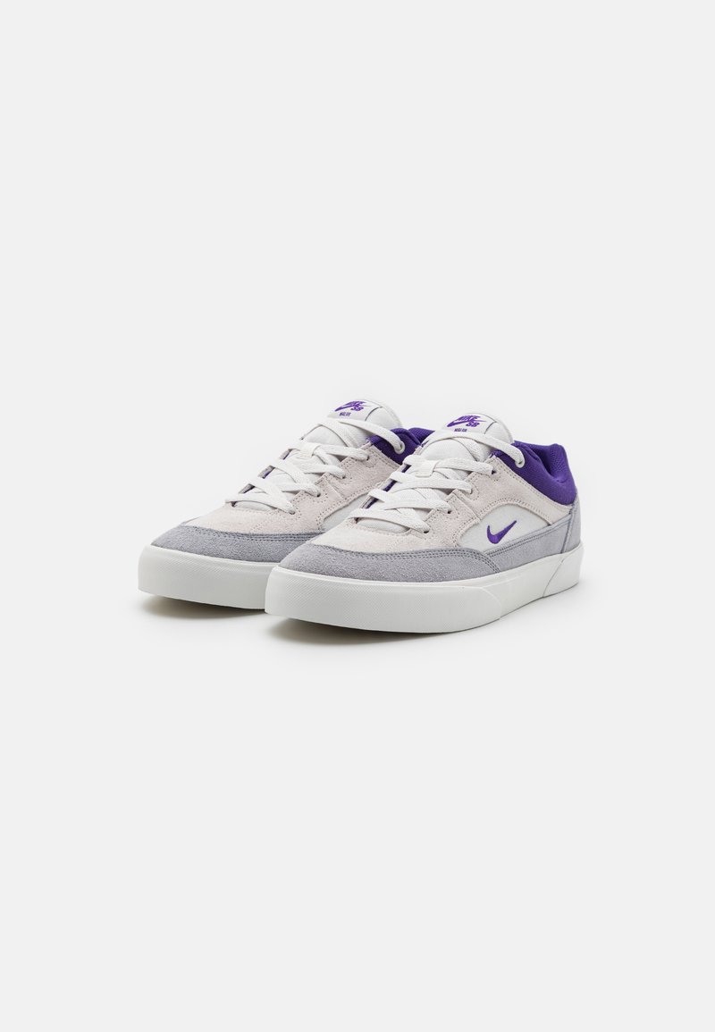 Graue und weiße Sneakers mit einem lila Akzent, ausgestattet mit einem Obermaterial aus Wildleder, runder Spitze, flacher weißer Sohle und Schnürverschluss.