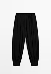 Schwarze, locker sitzende Hose aus weichem Stoff. Verfügt über einen elastischen Bund und verjüngte Bündchen an den Knöcheln. Glatte Textur, keine Muster.