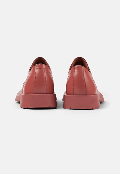 Red leather shoes with a smooth texture, rounded heel, and subtle stitching details, featuring a low-profile rubber sole.