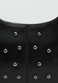 Crna kožna torba s ravnomjerno raspoređenim srebrnim zakovicama na površini, s gornjim zatvaračem na patent i glatkom teksturom.