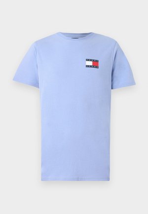 Hele sinise puuvillase lühikeste varrukatega T-särk, millel on ümmargune kaelus. Rinnal on väike ristkülikuline logo punaste, valgete ja tumesiniste aktsentidega.