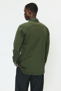 Overhemd met lange mouwen in donker olijfgroen, gemaakt van textuurstof. Voorzien van een puntige kraag en verstelbare manchetten.