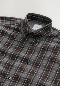 Chemise à carreaux marron et gris avec un col boutonné, une poche avant et des boutons contrastants ; fabriquée en tissu doux.