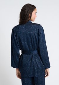 Accappatoio blu navy con motivo floreale, maniche lunghe e vita con cintura, caratterizzato da una texture liscia e un tessuto leggero.