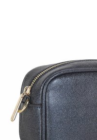 Struktureret sort lynlåspose med guldbeslag. Rundet form, flad bund og en glat lynlåslukning. Kompakt design med en subtil glans.