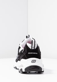 Svart- och vit sneaker med överdel i mocka och mesh, tjock vit sula och kontrasterande sömmar. Logotyp synlig på h älen.