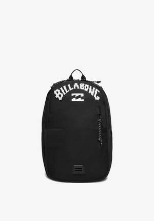 Black backpack with white Billabong logo, front zipper pocket, top handle, and a small rectangular patch near the bottom.