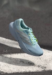 Αθλητικό παπούτσι σε ανοιχτό γαλάζιο με υφασμένο επάνω μέρος από πλέγμα, ασημένιες ρίγες και λαμπερές κίτρινες λεπτομέρειες. Διαθέτει κομψή σιλουέτα και ελαστική σόλα από καουτσούκ.