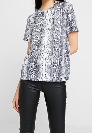 Camiseta de manga corta en estampado de serpiente blanco y negro, con un corte relajado y cuello redondo. Combinada con pantalones negros ajustados.