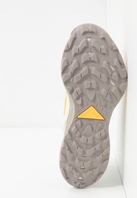Semelle de chaussure en caoutchouc gris à motif avec un accent triangulaire jaune. Conception durable avec une bande de roulement texturée pour la traction et la stabilité.
