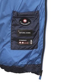 Interno di un giubbotto blu imbottito, presenta una tasca blu navy con un logo circolare e etichette per "NATURAL DOWN" e "INTERMEDIATE," e un'icona di temperatura.