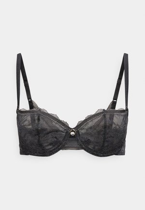 Czarny koronkowy biustonosz z fiszbinami, regulowanymi ramiączkami i małym złotym pierścieniem na środku przodu.