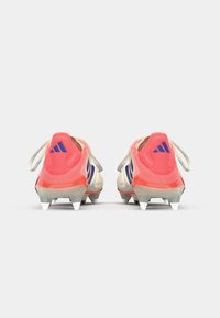 Adidas voetbalschoenen met een witte en roze bovenkant, paarse strepen, ronde hak en vijf witte noppen op een gestructureerde zool.