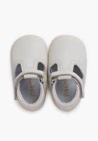 Zapatos de bebé de cuero blanco con puntas redondeadas, laterales troquelados y correas ajustables. Con detalles de marca en dorado y costuras decorativas.
