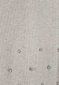 Tessuto grigio a righe con una superficie texturizzata, caratterizzato da ornamenti o borchie argento sparsi su tutto il materiale.