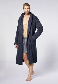 Dunkelblauer Bademantel aus strukturiertem Frottier, mit Kapuze, langen Ärmeln und großen Fronttaschen, getragen über grauen Shorts.