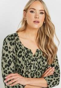 Grünes Leopardmuster-Shirt mit V-Ausschnitt, Dreiviertelärmeln und Knopfleiste. Weicher Stoff mit strukturiertem Erscheinungsbild.