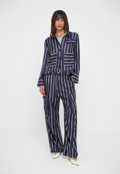 Completo con camicia a righe blu navy e pantaloni a gamba larga con orlo arricciato, caratterizzato da righe rosa chiaro in contrasto e numerose tasche.