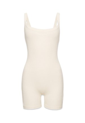 Beez värvi bodysuit õhukeste rihmadega, veniv ribakonstruktsioon, keha lähedane disain ja keskmise reisi pikkus. Ees on silt 'RAMANIA'.