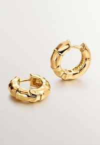 Pendientes de aro de oro con un diseño texturizado, similar al bambú. Presentan superficies redondeadas y brillantes, y un cierre de bisagra para asegurar.