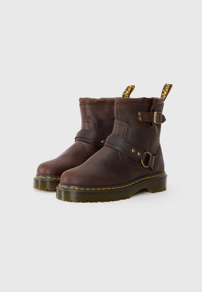 Bottes de cheville en cuir brun avec un détail de boucle et de sangle, couture jaune et une semelle en caoutchouc épaisse. Fini texturé, design robuste.
