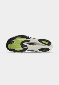 Semelle de chaussure de course avec motifs de grip noirs et verts et semelle intermédiaire blanche, affichant les marques PWRPLATE et PUMAGRIP.