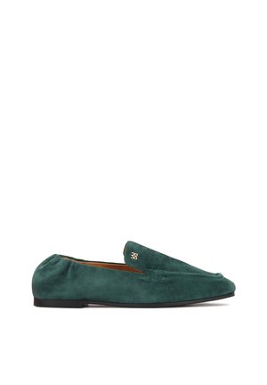 Mocassins en daim vert foncé à texture lisse, bout arrondi, et discret accent doré sur le côté. Semelle plate noire.