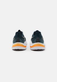 Zapatillas de correr azul y negras con acentos naranjas; parte superior de malla, cuello acolchado y suela blanca acolchada con textura antideslizante.