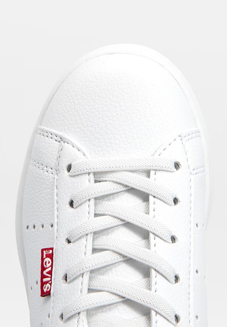 Baskets blanches en cuir texturé, avec des lacets plats, des détails perforés sur les côtés et un logo rouge Levi's sur le côté.