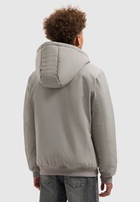 Grijze doorgestikte jas met een grote capuchon, geribbelde manchetten en zoom. Gladde buitenkant en een gestroomlijnde silhouet.