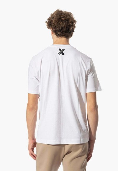 T-shirt bianca in cotone con maniche corte e scollo rotondo, presenta un logo X nero sulla parte posteriore vicino al collo.