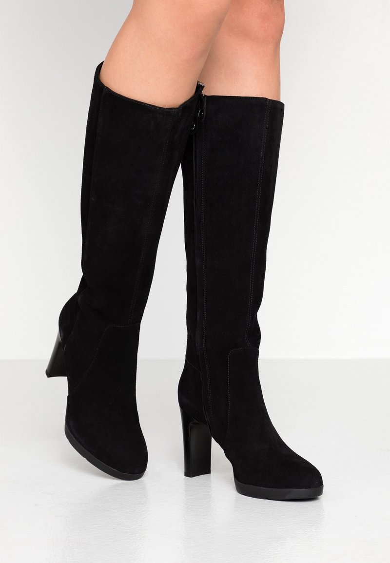Stivali alti in suede neri con tacco a blocco alto, caratterizzati da cuciture verticali e una chiusura con cerniera laterale per una facile vestibilità.