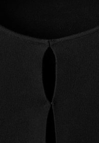 Top de punto negro con un destacado corte en forma de llave en el escote, con una textura suave y un acabado limpio alrededor de los bordes.