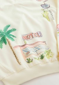 Tissu avec un palmier brodé et une enseigne vintage de motel affichant le mot « ouvert », accompagné de petites plantes vertes et de panneaux de diner.