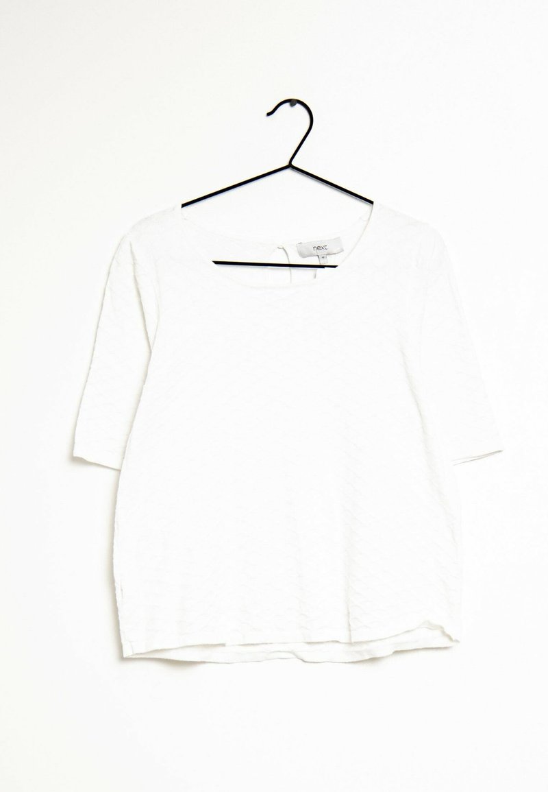 White short-sleeve top with a scoop neckline, featuring a textured pattern and a relaxed fit, hanging on a black hanger against a light background.