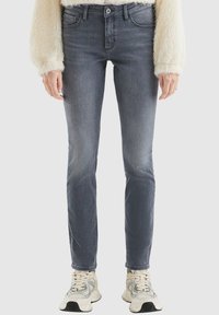 Slim-Fit graue Jeans aus Denim mit mittelhohem Bund, klassischem Fünf-Taschen-Design und Knopfverschluss, kombiniert mit hellen Sneakers.