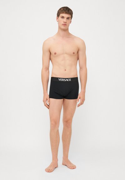 Zwarte boxershorts met een contrasterend wit "Versace" logo op de tailleband; aansluitend ontwerp en zachte stoftextuur.