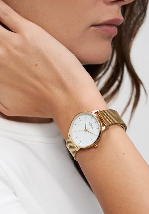 Goldene Netz-Armbanduhr mit weißem, rundem Zifferblatt und minimalistischen Markierungen. Das Armband hat ein strukturiertes Design und ist mit einer eleganten Schließe gesichert.