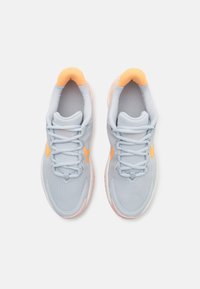 Baskets de course bleu clair avec accents orange, tige texturée, col rembourré et semelle en caoutchouc. Comprend des lacets et des détails de logo.