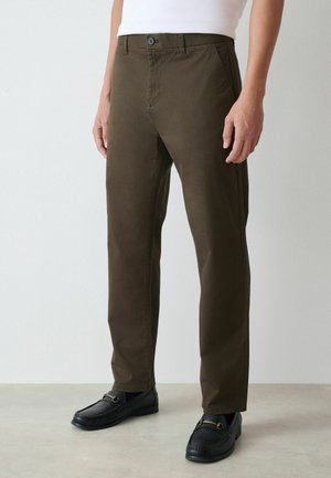 Oliivivihreät housut, joissa on kapea malli, valmistettu puuvillasekoitetekstiilistä; varustettu nappisululla, vinon sivutaskuilla ja sileällä pinnalla.