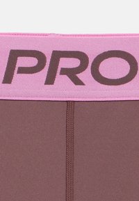 Nahaufnahme von braunem Stoff mit einem rosa Bund, auf dem große, fett gedruckte Buchstaben "PRO" in dunkelbraun gestickt sind.