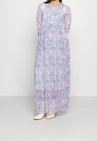 Maxi sukienka w kwiatowy wzór z pastelowymi kolorami: fioletowym, różowym i niebieskim. Długie rękawy i lekka tkanina z dopasowanym fasonem.