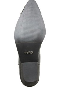 Suela de zapato de piel negra con una superficie texturizada, que presenta un logotipo prominente y un acento metálico. La forma es puntiaguda con un ligero tacón.