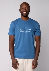Blaues Baumwoll-T-Shirt mit weißen Aufdruck, auf dem steht "Das ist aber ein schöner Baum." Kurze Ärmel und runder Halsausschnitt.