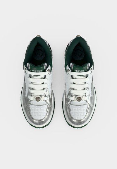 Paire de baskets blanc et argenté Versace avec doublure verte, lacets blancs et détail médaillon Méduse sur la zone des orteils, vue de dessus.