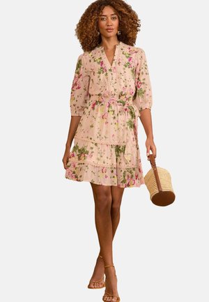 Il vestito floreale presenta una base rosa con fiori verdi e viola, una chiusura con bottoni, volant a strati e maniche a lunghezza gomito. Include una borsa intrecciata.