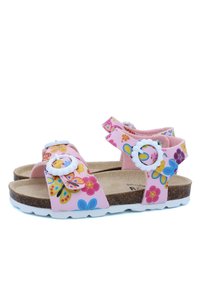 Sandales roses avec des motifs floraux et de papillons, brides ajustables, semelle intérieure en liège et semelles en caoutchouc blanches. Accent notable avec des éléments en métal circulaires.